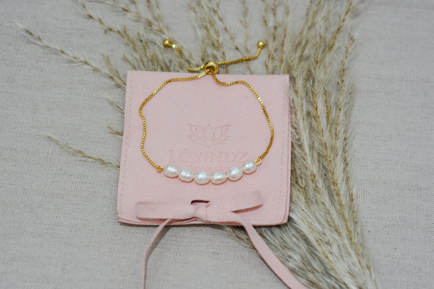 Pulsera ajustable, hecha en perla de río y chapa de oro de
18 kilates